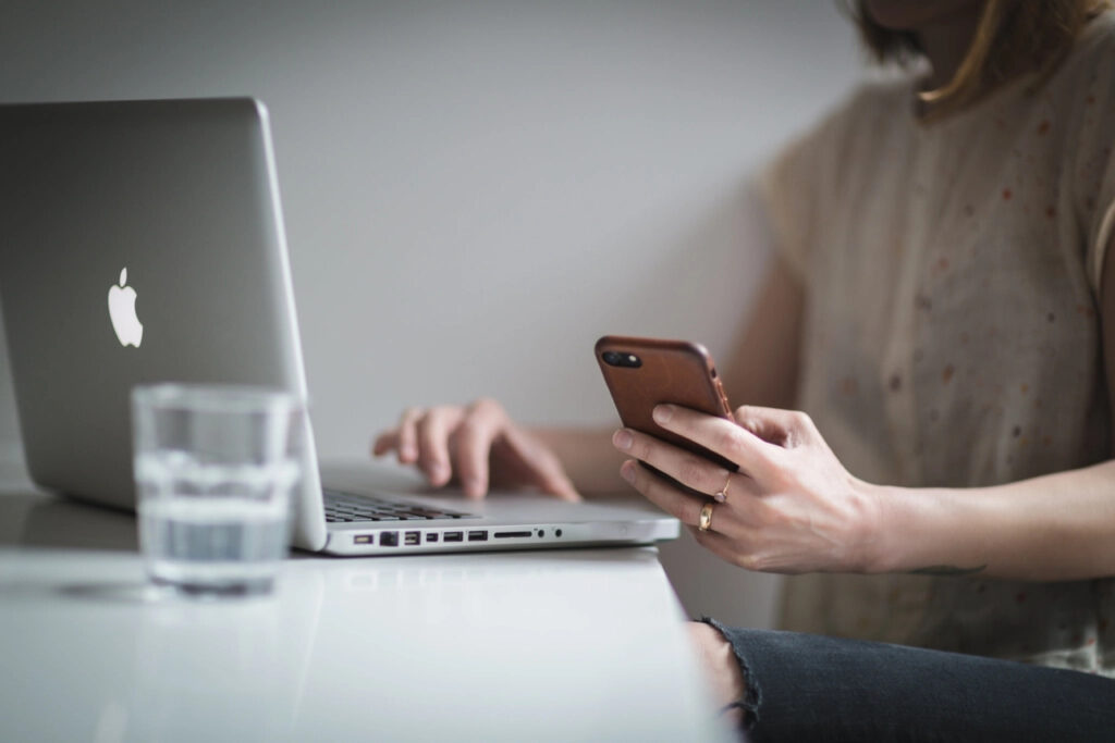 Woman checking her phone beside an open laptop
