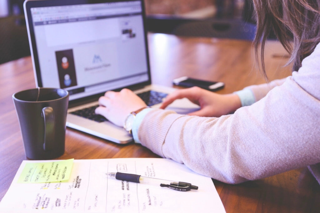 Woman working through tasks on a laptop at a wooden desk